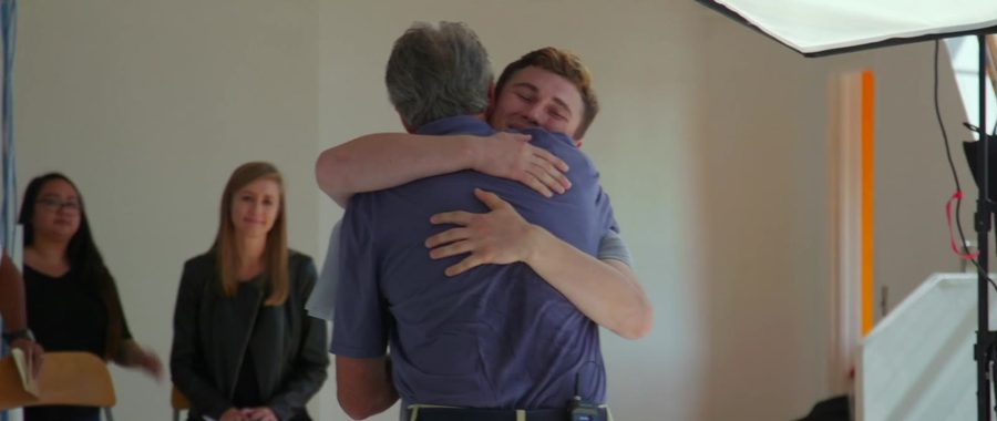 Two men embrace while others look on