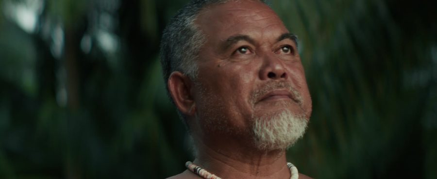 An elder in a shell necklace looks up